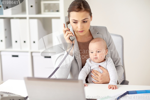 Image of businesswoman with baby calling on phone at office