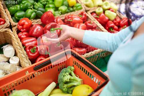 Image of woman with basket buying peppers at grocery store