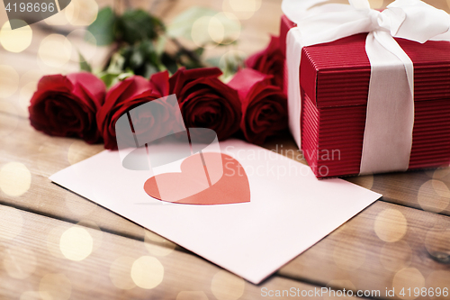 Image of close up of gift box, red roses and greeting card