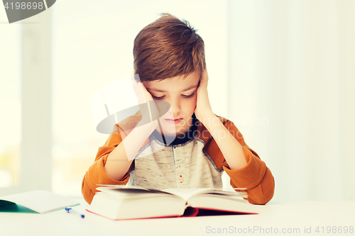 Image of student boy reading book or textbook at home