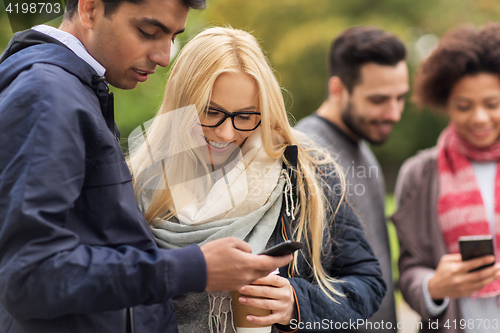 Image of happy friends with smartphone and coffee outdoors