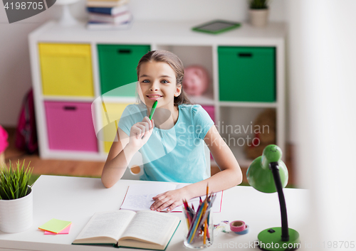 Image of happy girl with book writing to notebook at home