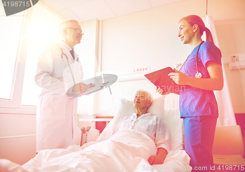 Image of doctor and nurse visiting senior woman at hospital