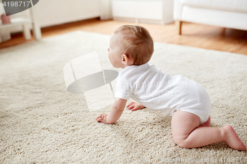 Image of little baby in diaper crawling on floor at home