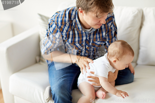 Image of happy young father with little baby at home