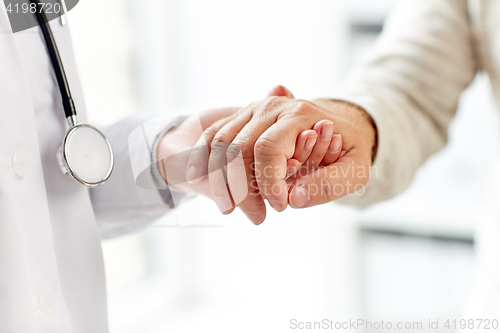 Image of close up of doctor holding old man hand