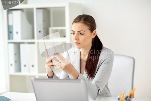 Image of businesswoman with smartphone at office