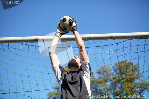 Image of goalkeeper with ball at football goal on field