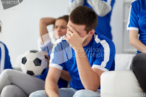 Image of unhappy man with friends or football fans at home