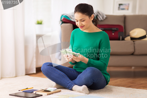 Image of happy woman with money and travel map at home