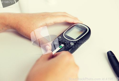 Image of close up of woman making blood test by glucometer