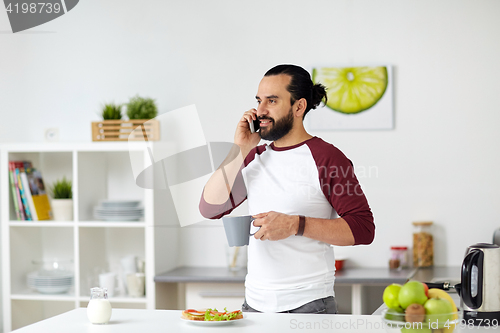 Image of man calling on smartphone and eating at home