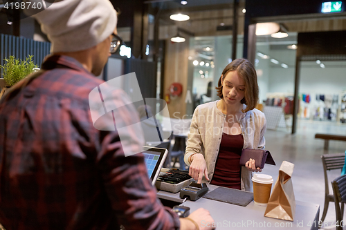 Image of happy woman paying for purchases at cafe