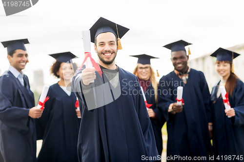 Image of happy students in mortar boards with diplomas