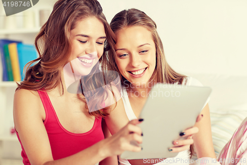 Image of happy friends or teen girls with tablet pc at home