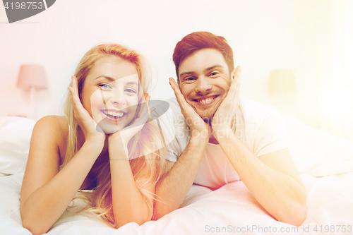 Image of happy couple lying in bed at home