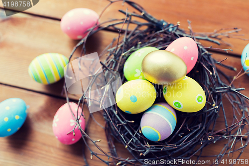 Image of close up of colored easter eggs in nest on wood