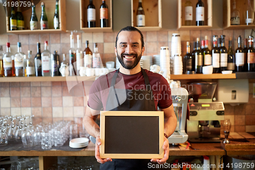 Image of happy man or waiter with chalkboard banner at bar