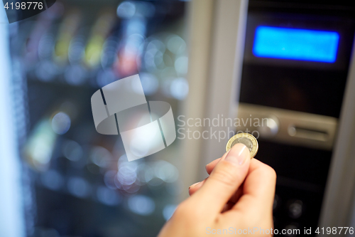 Image of hand inserting euro coin to vending machine slot