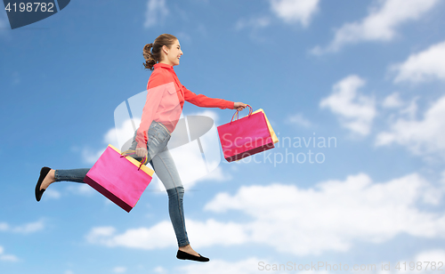 Image of smiling young woman with shopping bags running