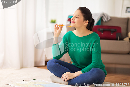 Image of happy young woman with travel map at home