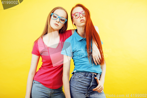 Image of lifestyle people concept: two pretty school girl having fun on yellow background, happy smiling students 