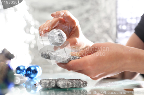 Image of Glitter bauble. A woman showering Christmas bauble silver glitter.