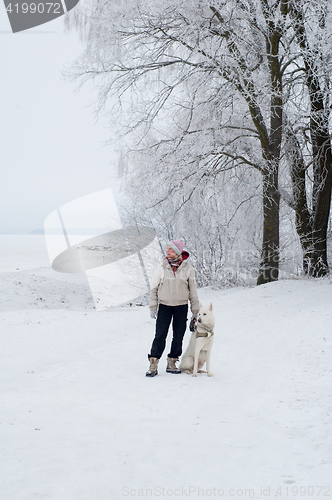 Image of Woman walking with a dog in winter