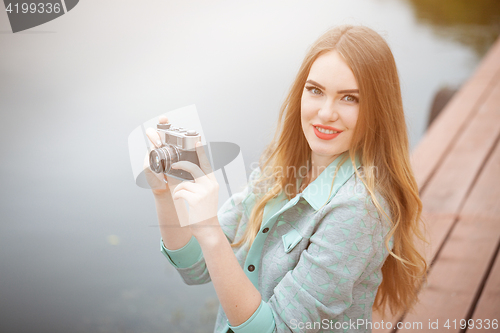 Image of Pretty young woman traveling with photo camera and making pictures