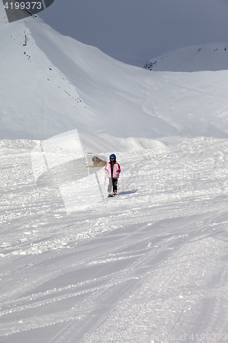 Image of Little skier on ski slope at sun winter day and gray sky before 