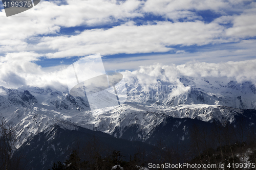 Image of View on snow mountains and sunlight cloudy sky at winter evening
