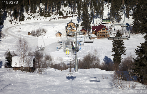 Image of Skiers on chair-lift at ski resort in sun winter day