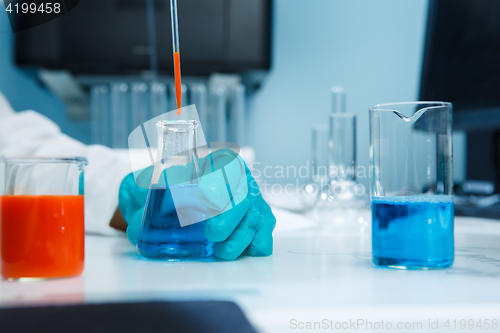 Image of Laboratorian with flask on table