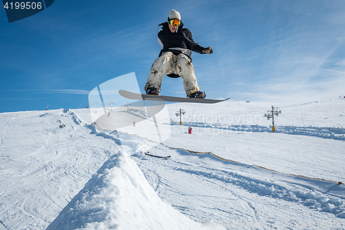 Image of Snowboarder jumping against blue sky