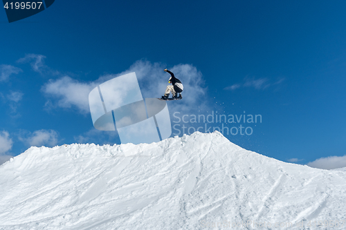 Image of Snowboarder jumping against blue sky