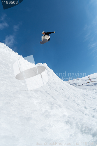 Image of Snowboarder jumping against blue sky