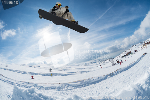 Image of Snowboarder jumping against blue sky