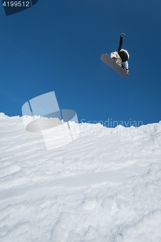 Image of Snowboarder jumping against blue sky