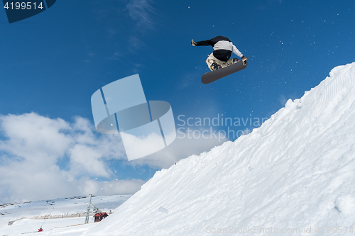 Image of Snowboarder jumping against blue sky