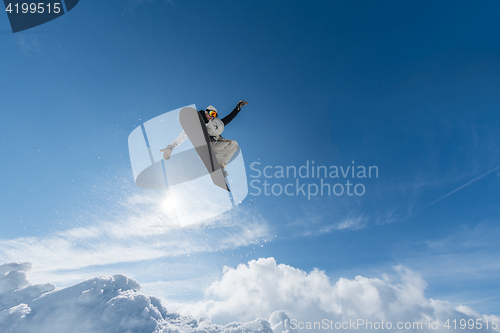 Image of Snowboarder jumping against blue sky