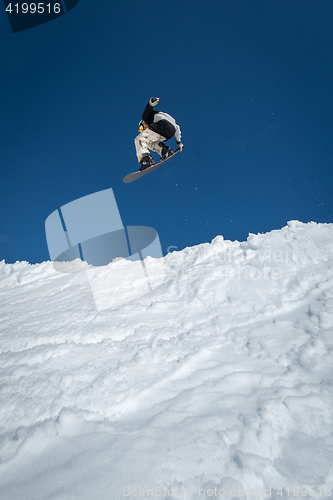 Image of Snowboarder jumping against blue sky