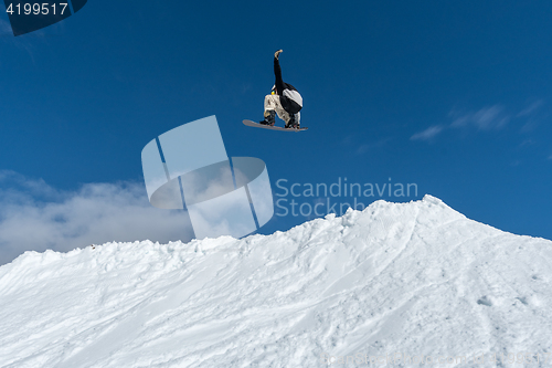 Image of Snowboarder jumping against blue sky