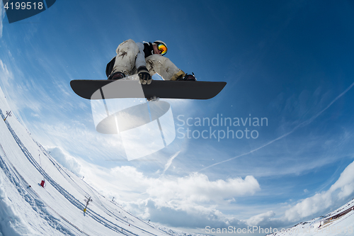 Image of Snowboarder jumping against blue sky