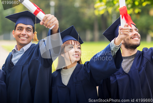 Image of happy students in mortar boards with diplomas