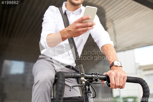 Image of man with smartphone and fixed gear bike on street