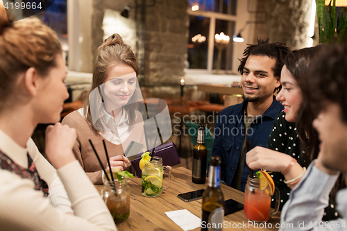 Image of friends with drinks, credit card and bill at bar