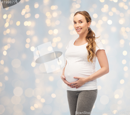 Image of happy pregnant woman touching her big belly