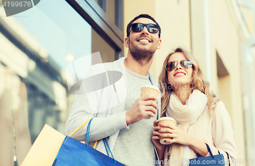 Image of happy couple with shopping bags and coffee in city