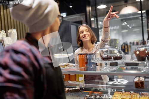 Image of happy woman showing something to bartender at cafe