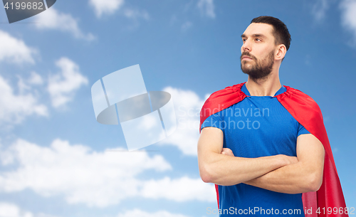 Image of man in red superhero cape over blue sky